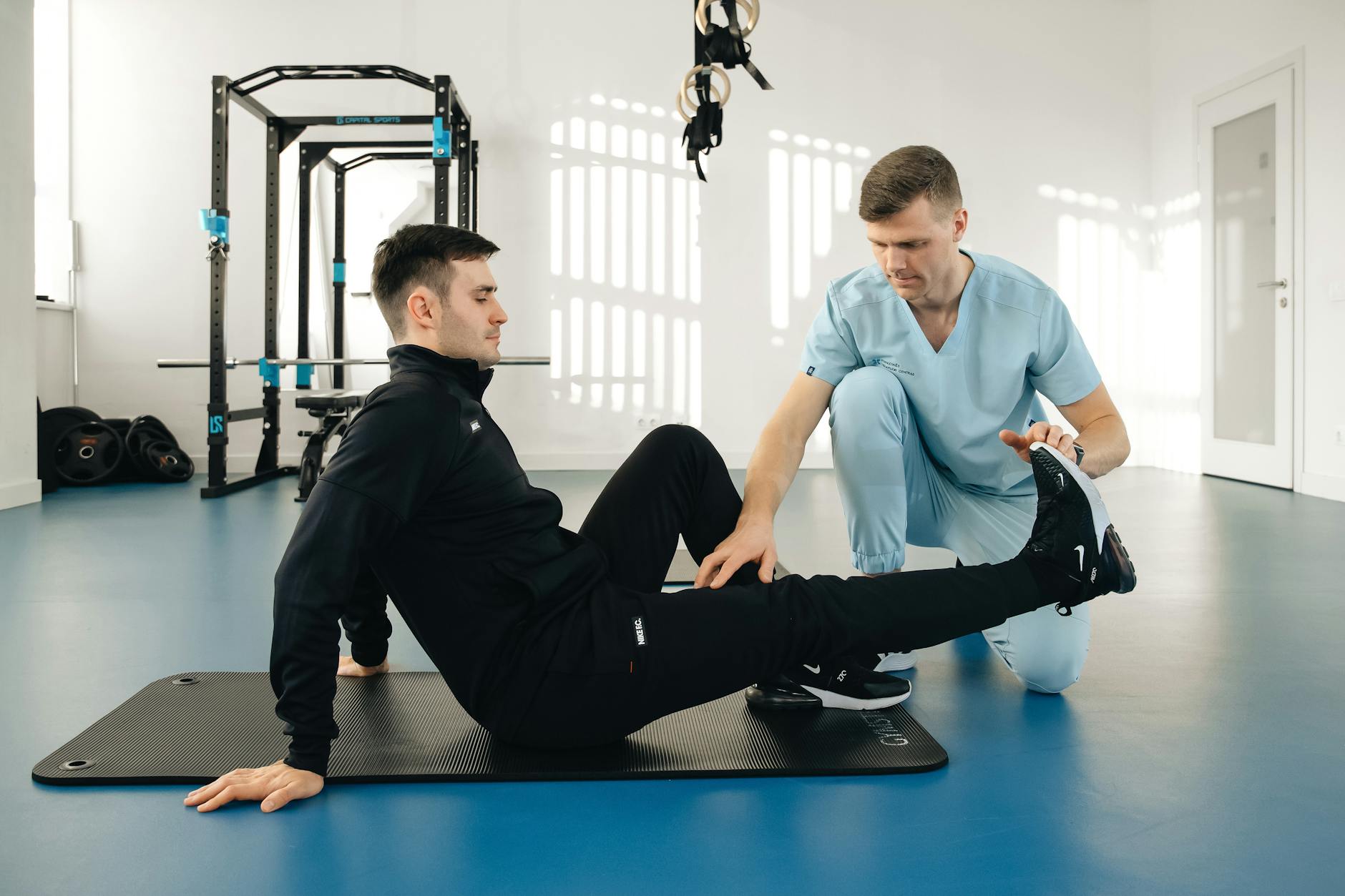 Fizjoterapeuta prowadzi ćwiczenia rehabilitacyjne z mężczyzną w nowoczesnej sali