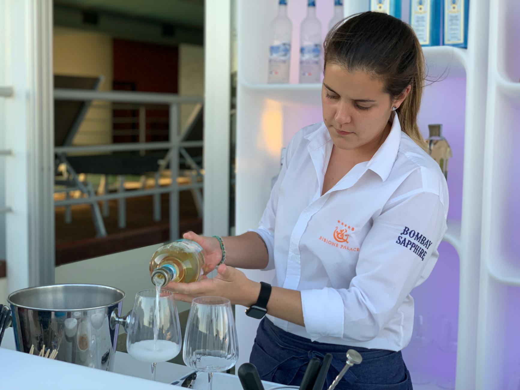 Barman w białej koszuli nalewa drinki w plenerowym barze weselnym