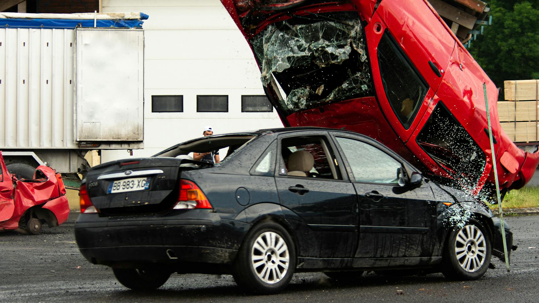 Czerwony samochód przewrócony na czarne auto po kolizji na drodze