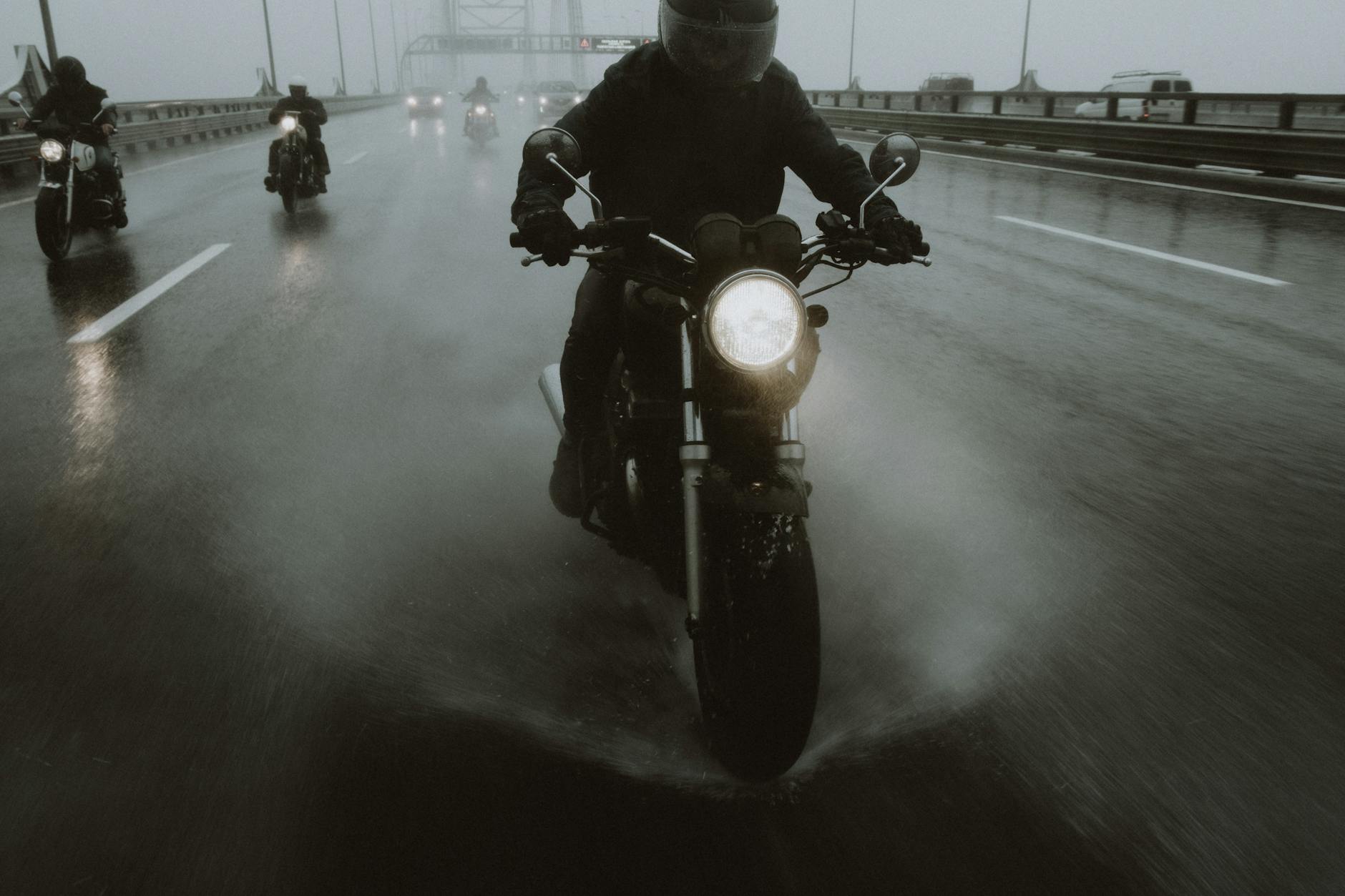 Motocykliści jadący w deszczu autostradą, woda bryzga spod kół