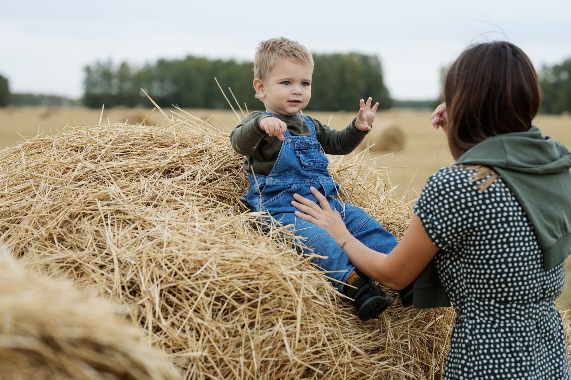 Mama bawi się z małym synkiem na stogu siana na wsi