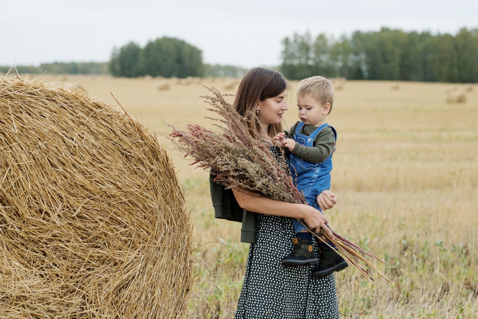 Mama z dzieckiem i bukietem polnych kwiatów na słonecznej łące