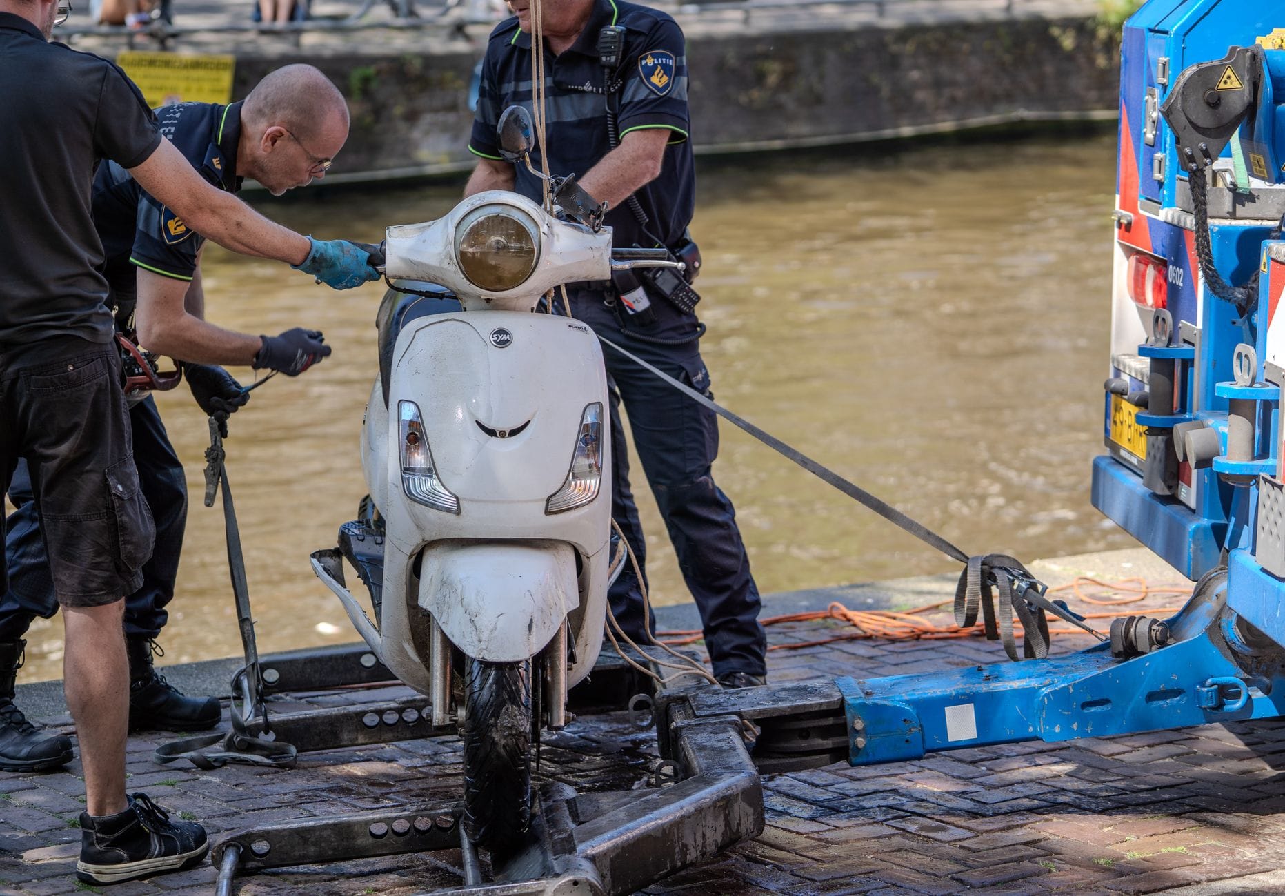Policjanci wyciągają skuter z kanału za pomocą sprzętu holowniczego