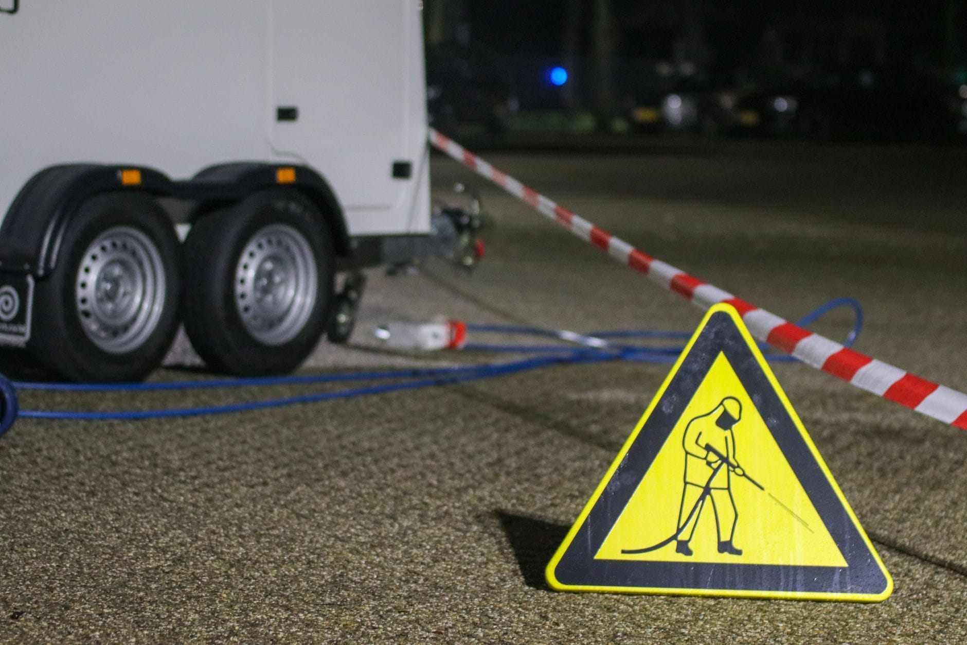 Taśma ostrzegawcza i znak budowy nocą obok zaparkowanej lawety