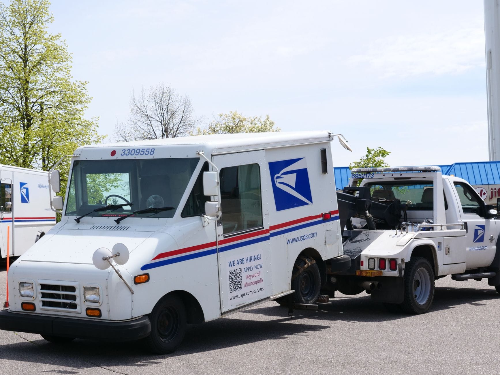 Laweta holuje samochód pocztowy USPS na zewnątrz w słoneczny dzień