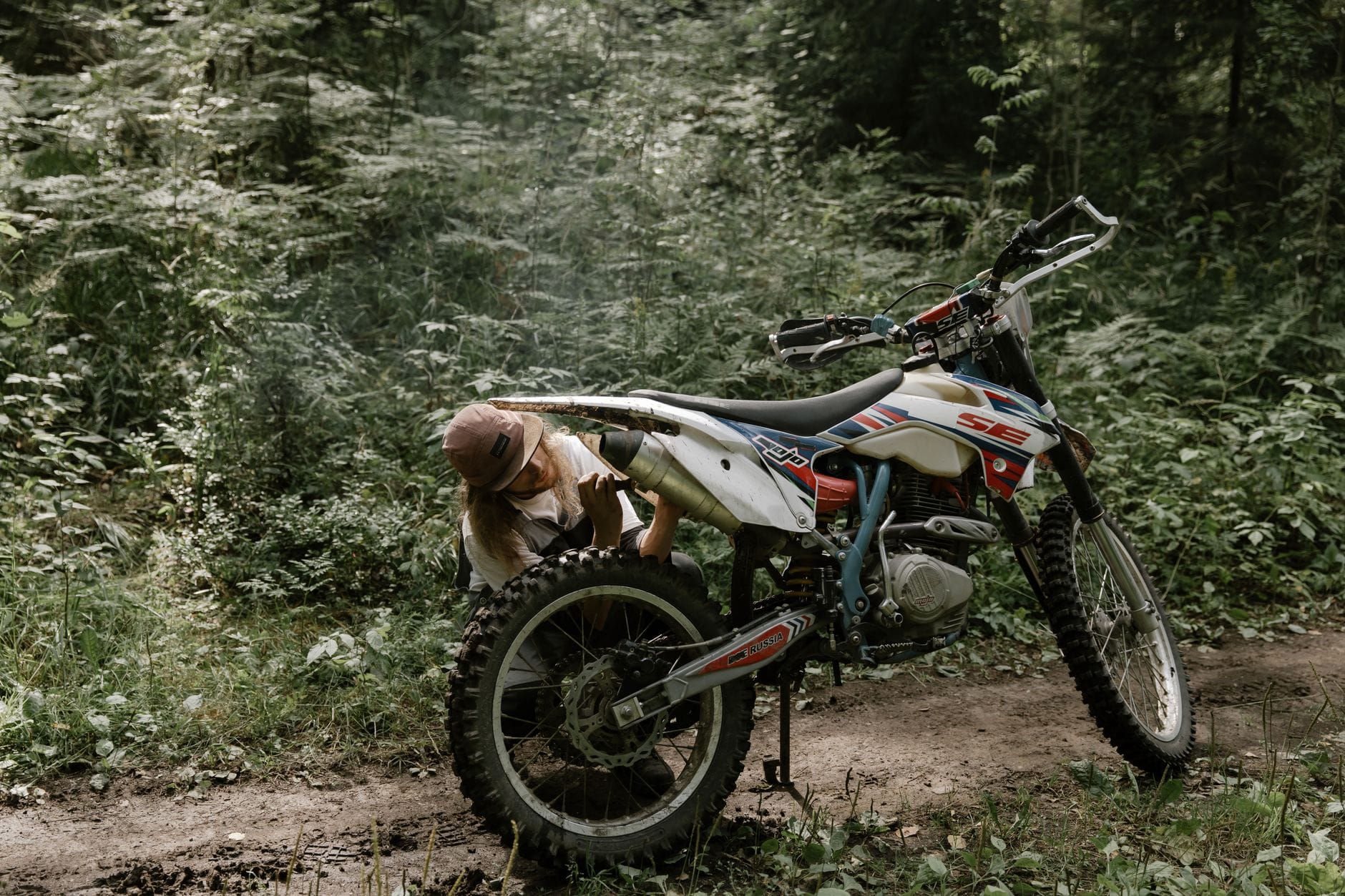 Motocyklista naprawia motocykl terenowy na leśnym szlaku