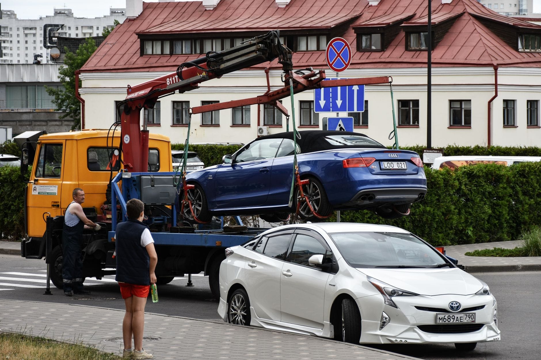Niebieskie Audi kabriolet holowane na ruchliwej miejskiej ulicy